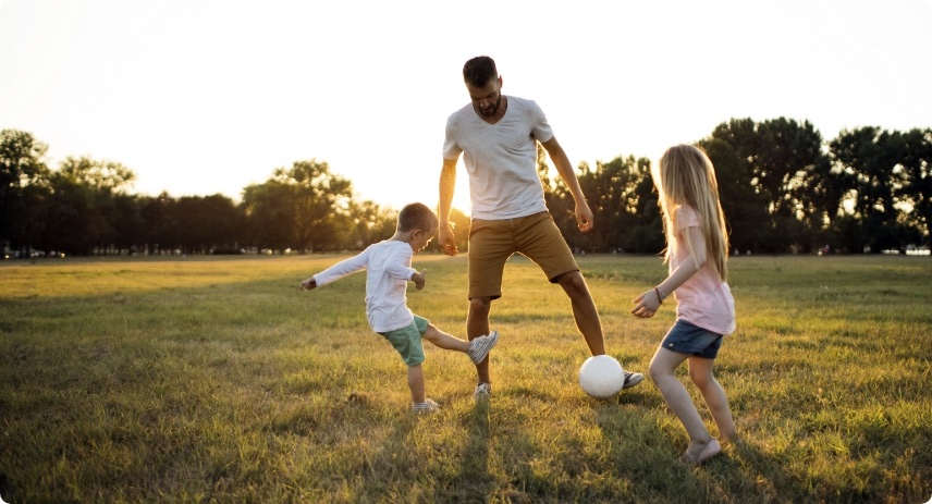 A man playing soccer with two kids. 