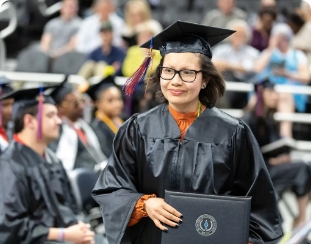 A new graduate walks with her diploma. 