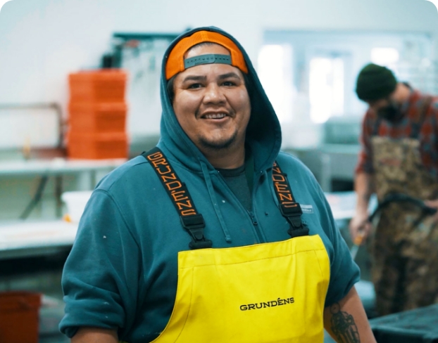 A man in an apron smiling while working in a kitchen. 