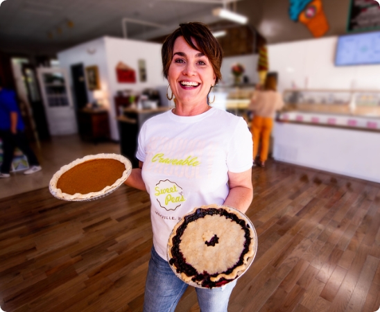 Woman holding pies in a bakery.