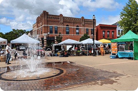 Image of water fountain and vendors at Stevens Point farmers market.