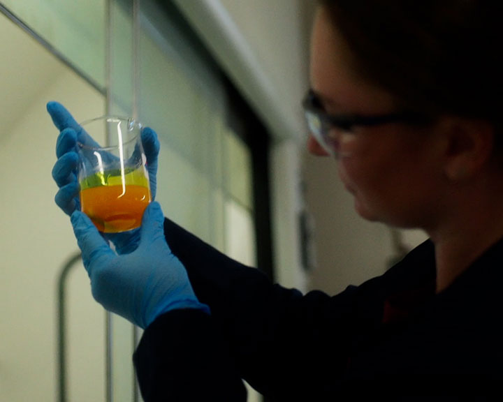 Woman examining a beaker of chemicals