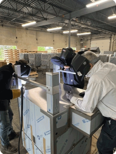 Welders assembling a Madigo parts washing machine