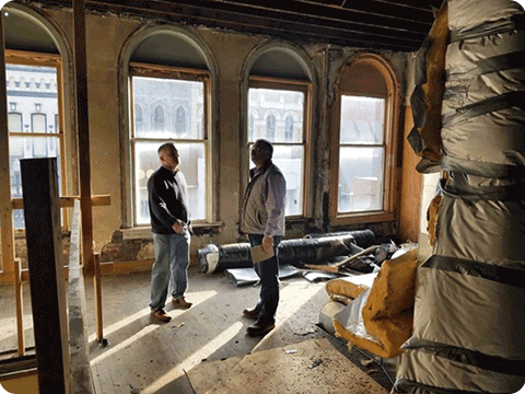 Two men reviewing insulation in a room with large windows.