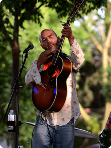 Man playing guitar at outdoor concert.