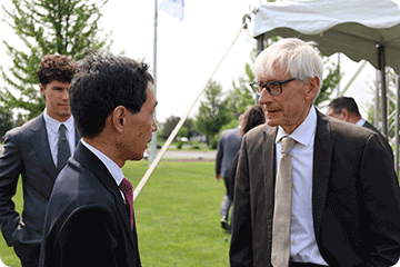 Gov. Tony Evers speaks with Yaskawa executive at ceremony.