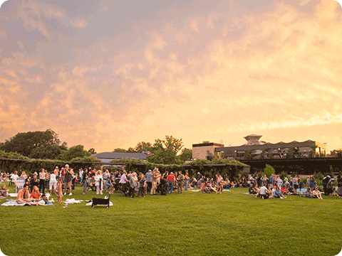 Dozens of people sitting on the grass at Olbrich Botanical Gardens, Madison.