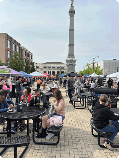 People sitting at tables at Monument Square in downtown Racine, WI.
