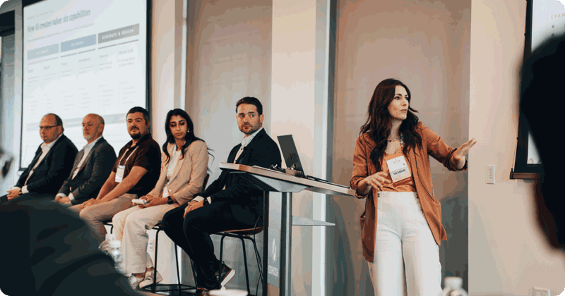 Woman presenting with a panel at 2026 Tech Summit with seated audience.