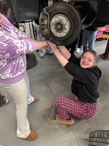 Two female students from Arcadia High School working on a car's breaks.