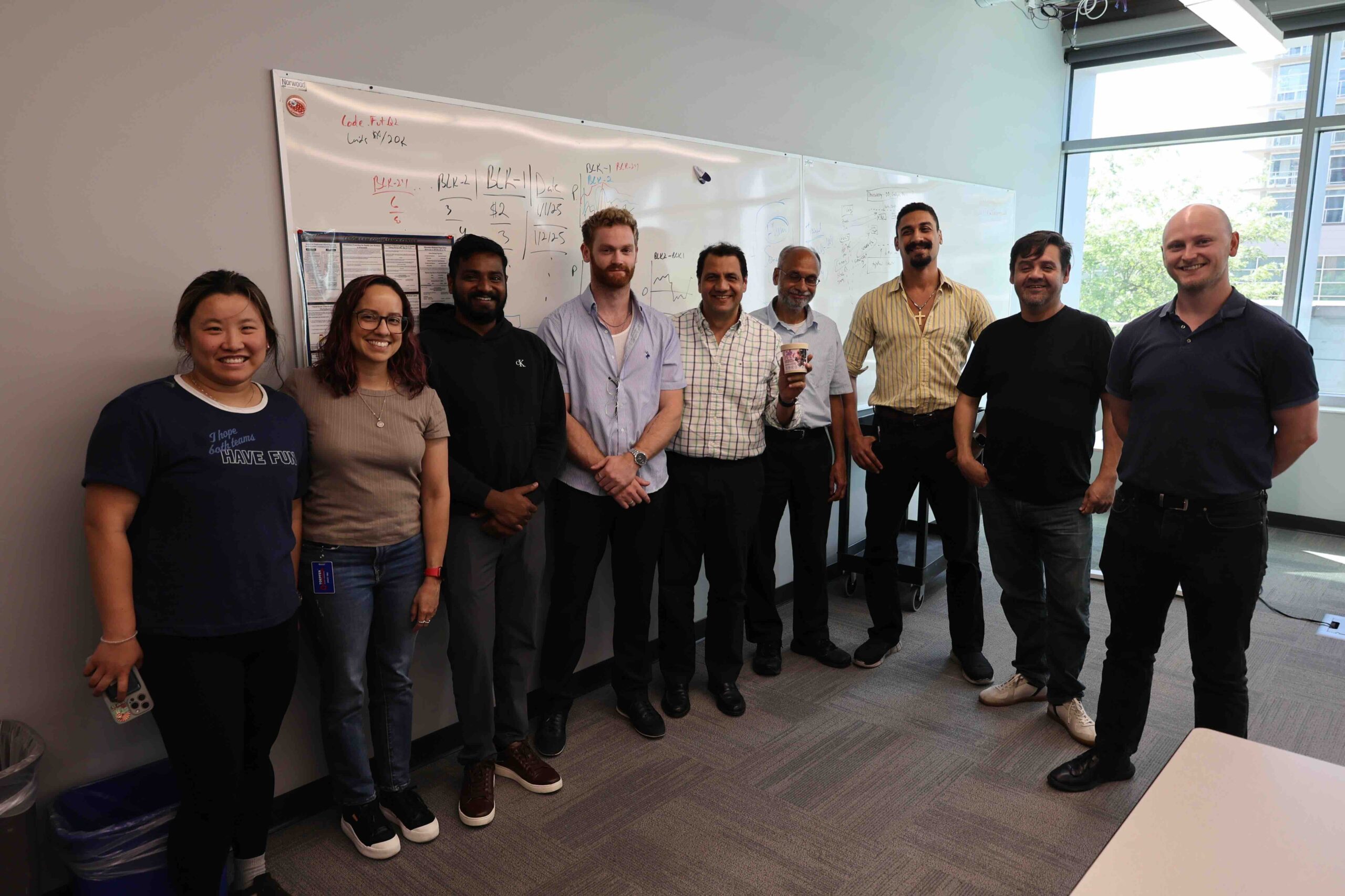 A team of nine Wisconsin founders pose for a photo in an office meeting room in front of a whiteboard.
