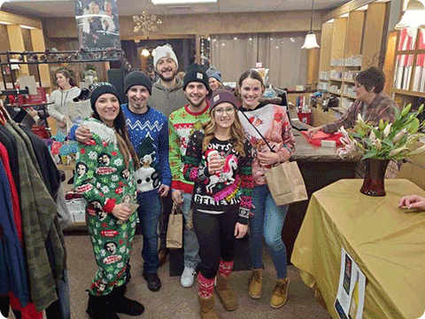 Young adults wearing Christmas sweaters and participating in a community event.