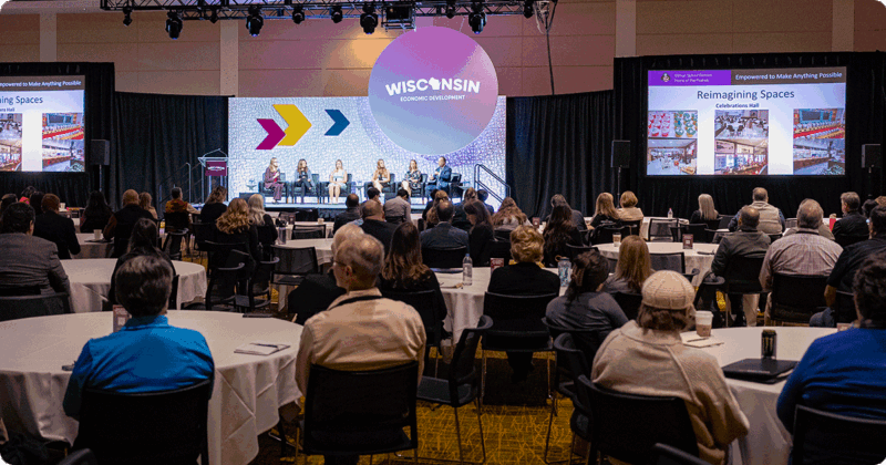 Panel discussion with audience members sitting at round tables at the Wisconsin Economic Summit.