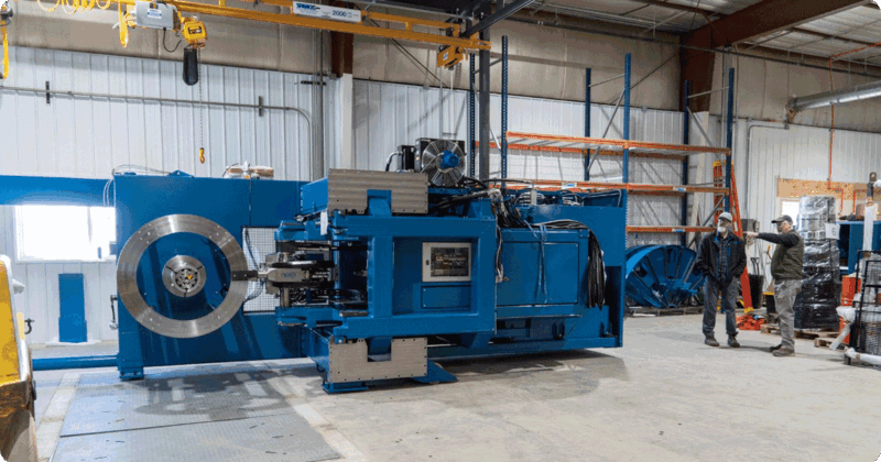 Two men pointing at a large blue industrial fans being prepared for shipping