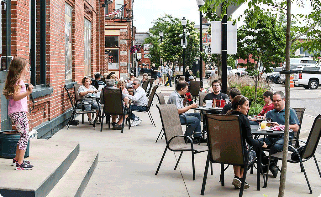 People sitting at round tables on the sidewalk in Stevens Point.